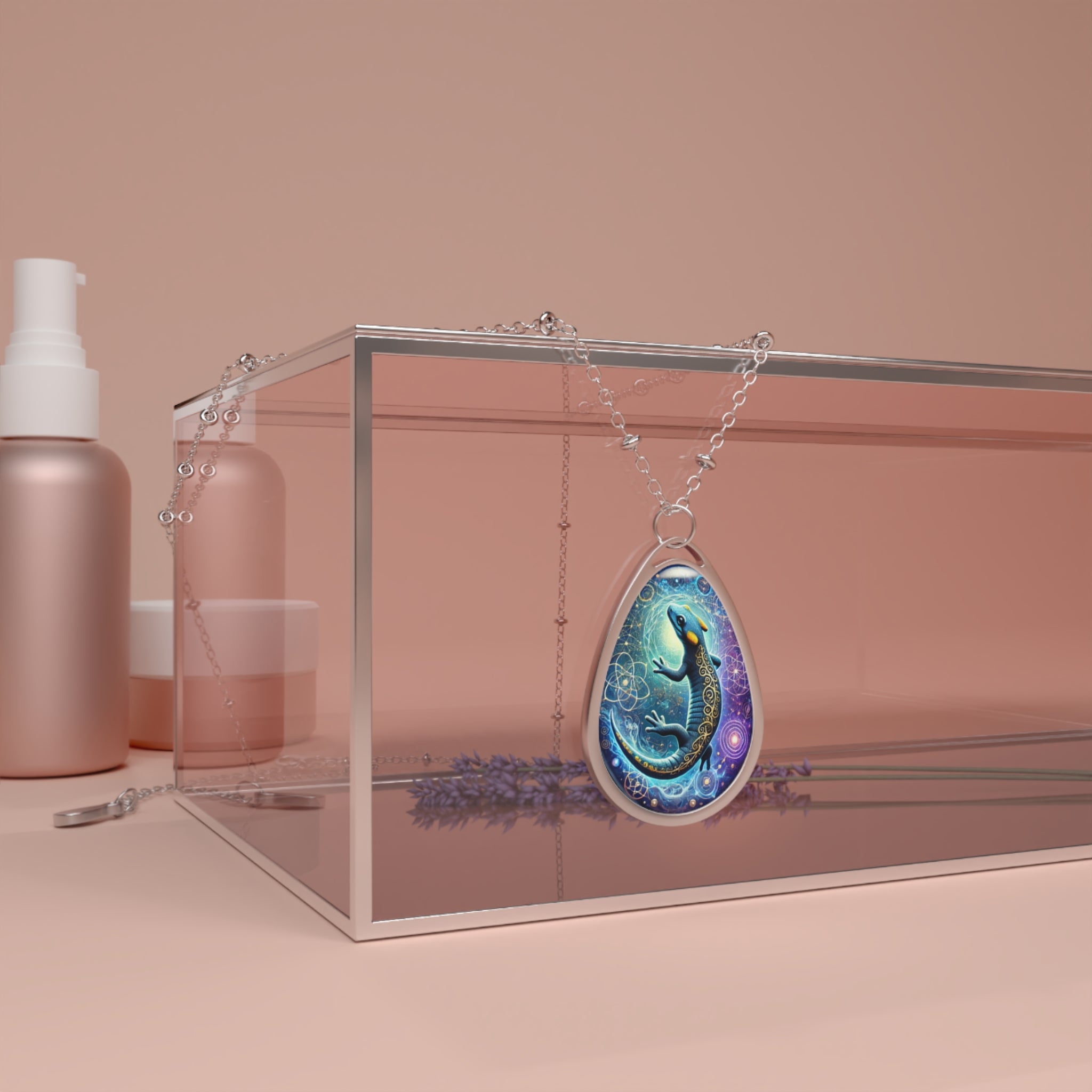 A decorative salamander necklace draped over a transparent glass jewelry box with a soft pink hue. The pendant features an intricate celestial-themed salamander with blue and purple tones, placed alongside delicate lavender sprigs.