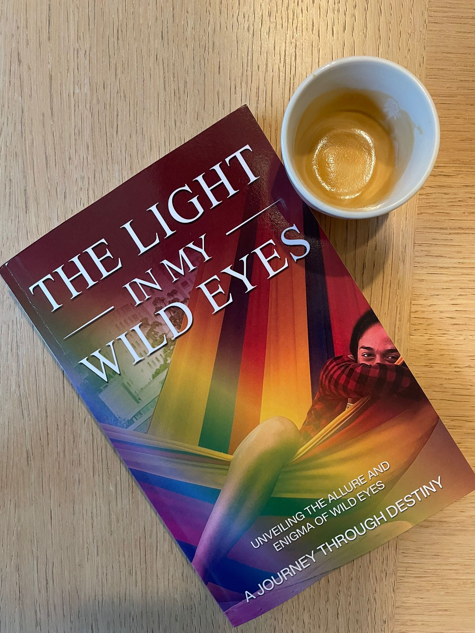 Enjoying 'The Light in My Wild Eyes' alongside a finished cup of espresso, pairing the warmth of coffee with the richness of a personal journey unfolded through the pages.