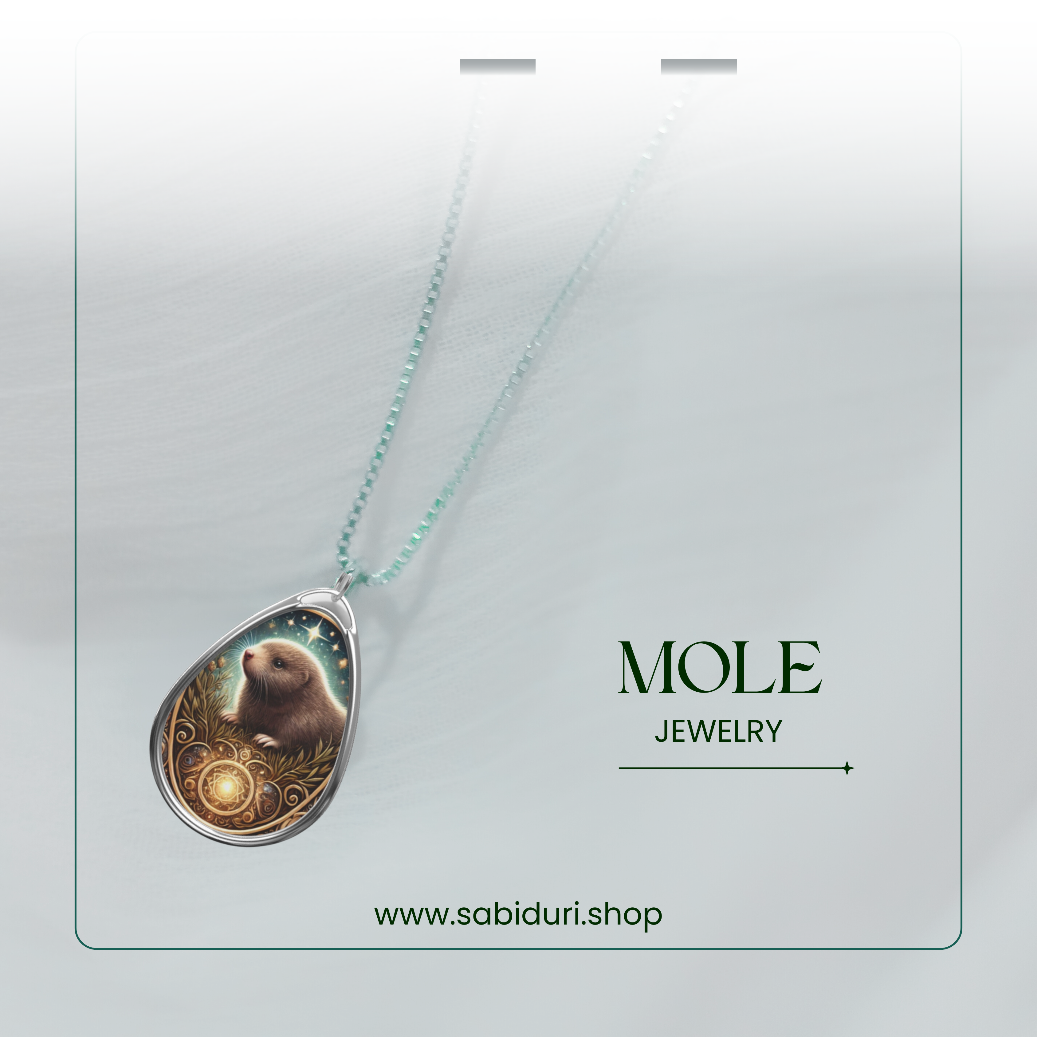 A mole pendant necklace displayed on a soft, airy white background, with a delicate silver chain complementing the intricate charm. The mole appears nestled in nature, with a glowing gemstone at the base. "MOLE JEWELRY" is elegantly written beside it, along with "www.sabiduri.shop."