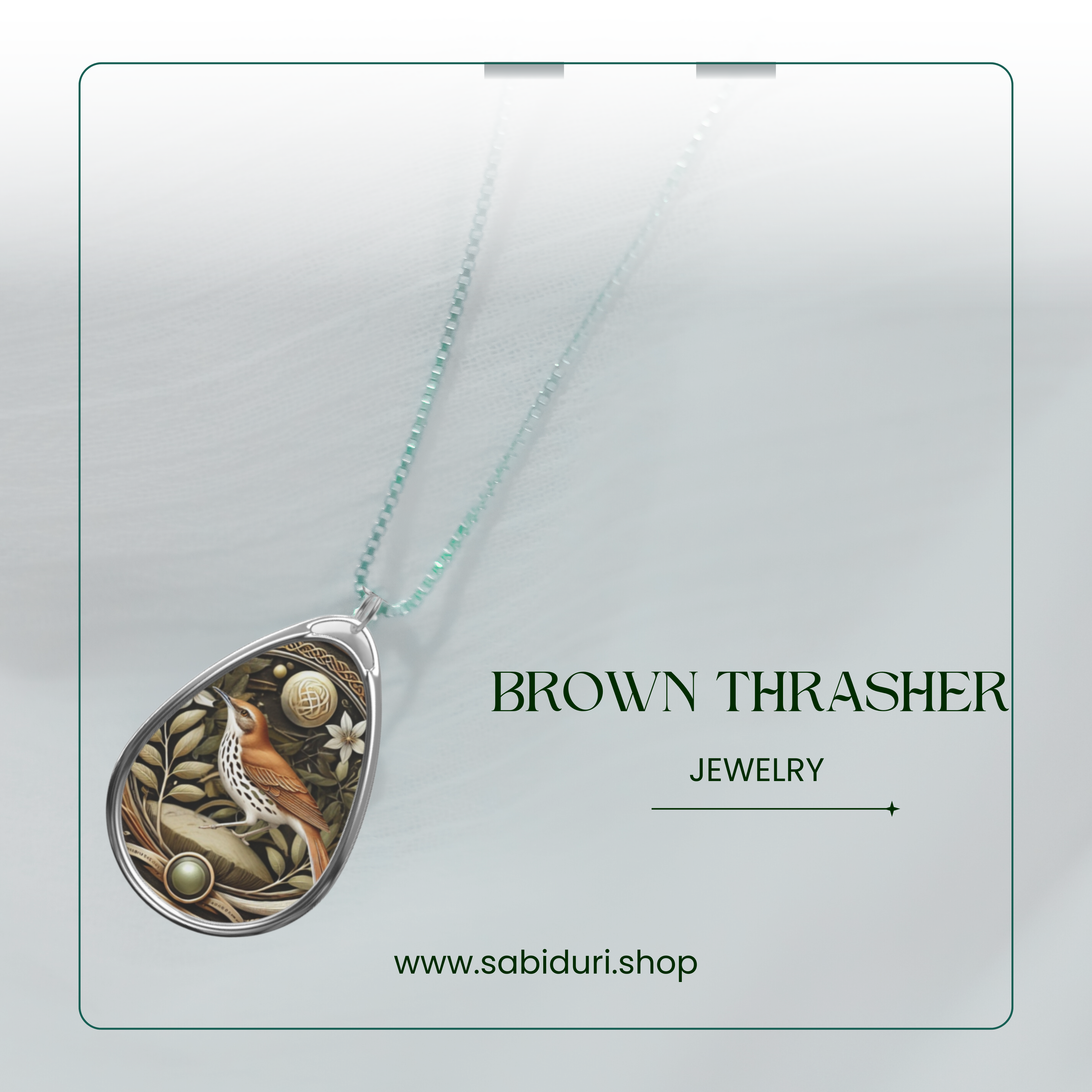 A close-up view of the Brown Thrasher spirit animal necklace on a white background, featuring a beautifully detailed bird design within a teardrop-shaped pendant and subtle green and gold embellishments