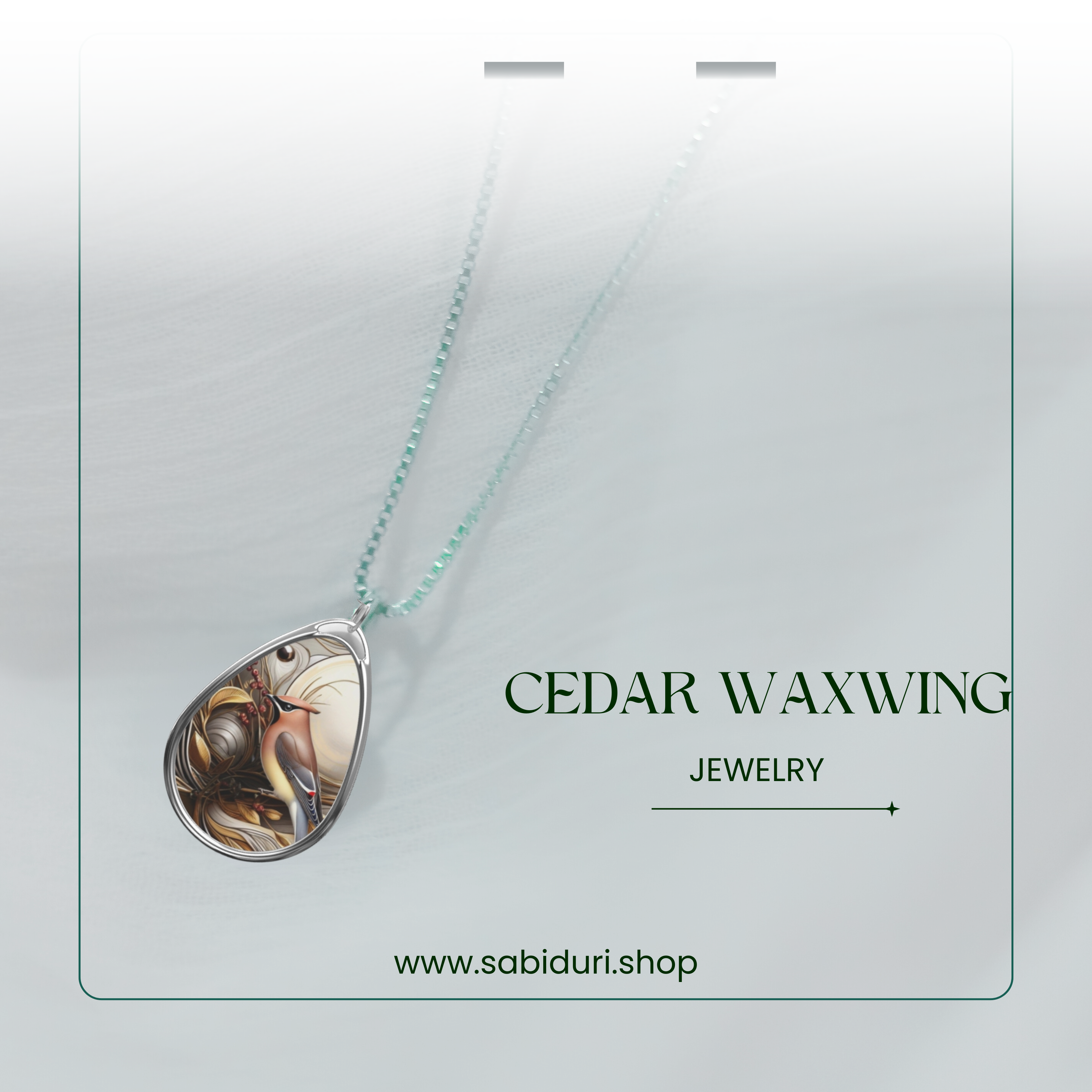 A silver teardrop pendant featuring an intricate illustration of a cedar waxwing bird perched among detailed foliage and berries. The necklace hangs from a delicate beaded chain, presented against a soft, white gradient background with the text "Cedar Waxwing Jewelry" and "www.sabiduri.shop" displayed elegantly.