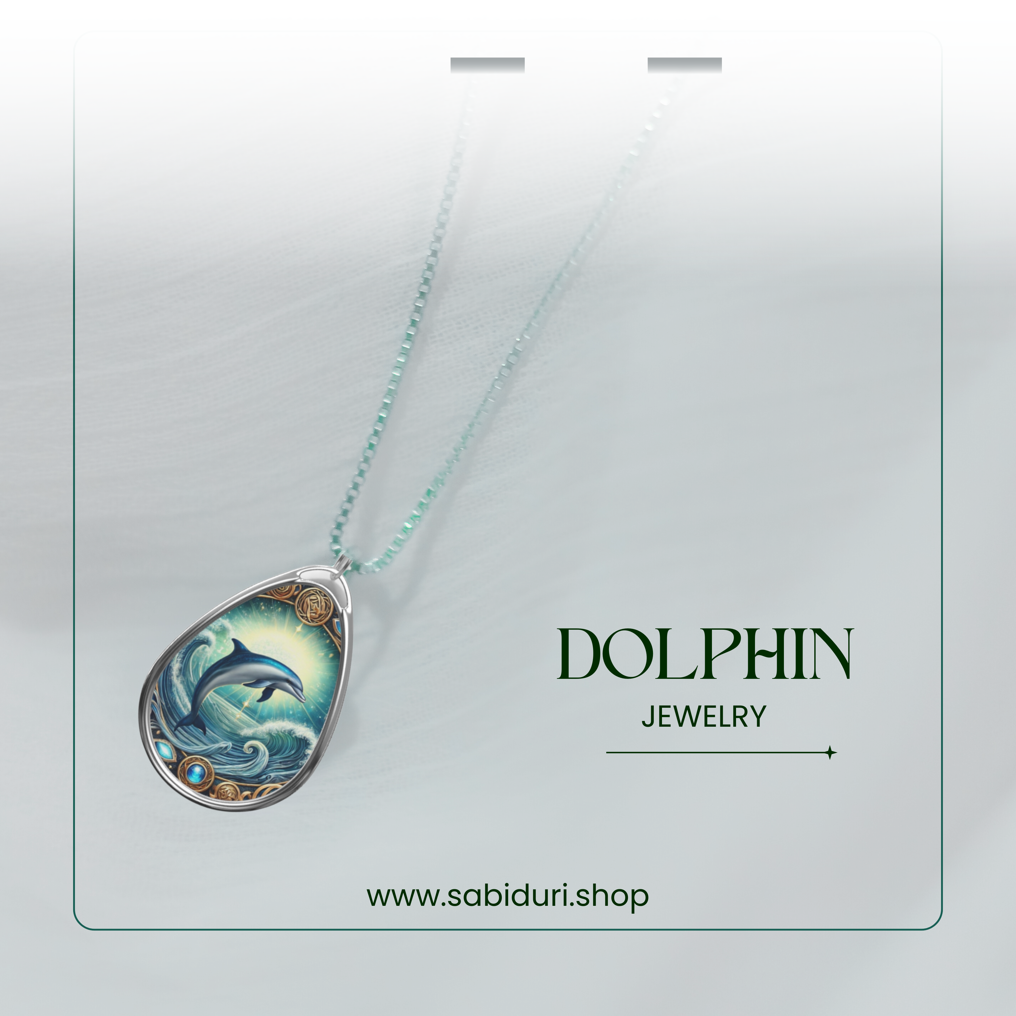 The Dolphin necklace elegantly displayed on a soft, white fabric background. The silver pendant, with its intricate dolphin and ocean wave motif, is attached to a fine silver chain with delicate blue-green beads. The text "DOLPHIN JEWELRY" and "www.sabiduri.shop" appear in a refined font.