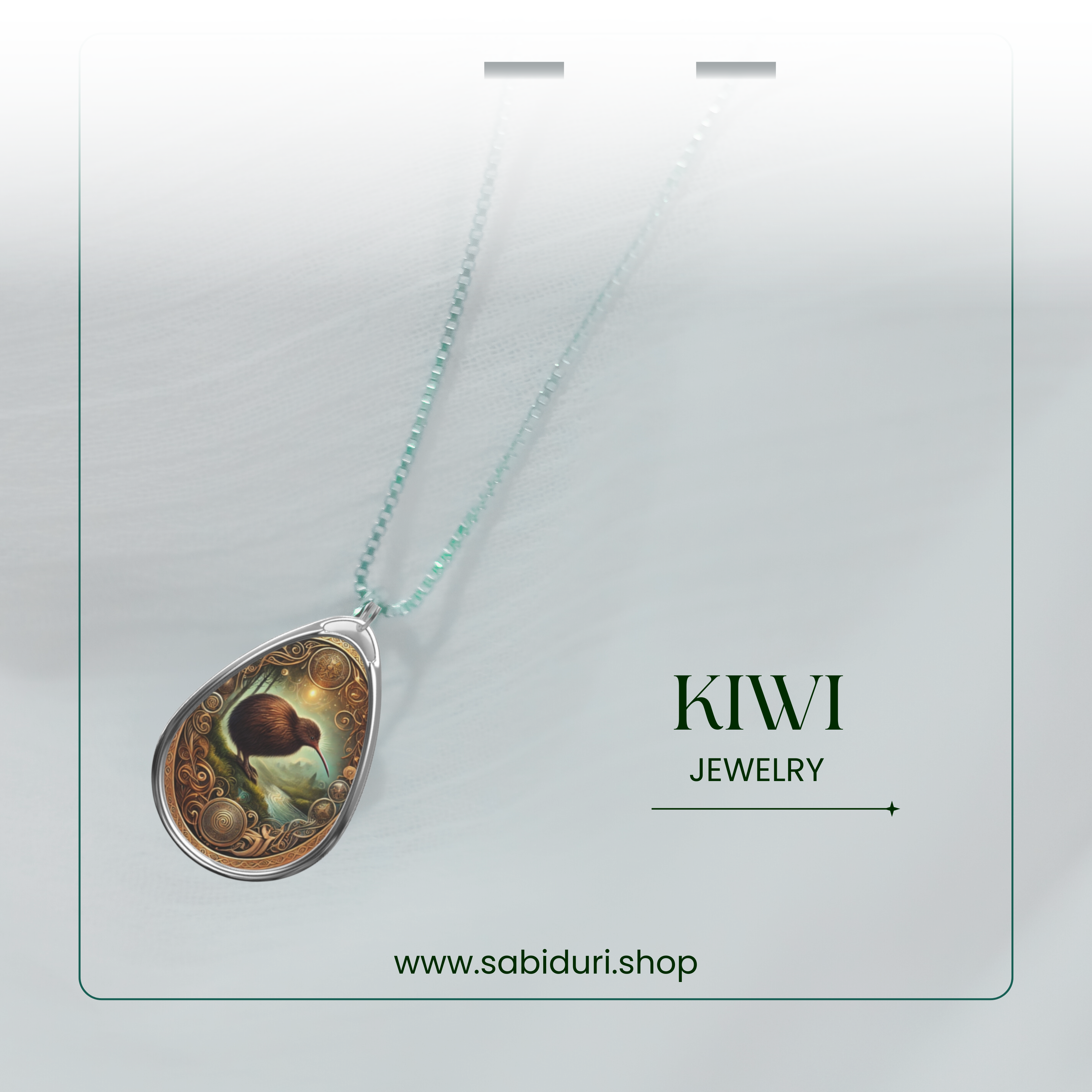 A delicate Kiwi spirit animal necklace displayed against a soft, ethereal white background. The teardrop-shaped pendant showcases a beautifully detailed kiwi bird within an ornate golden frame, suspended on a silver chain. Text reads 'KIWI JEWELRY' and 'www.sabiduri.shop.'