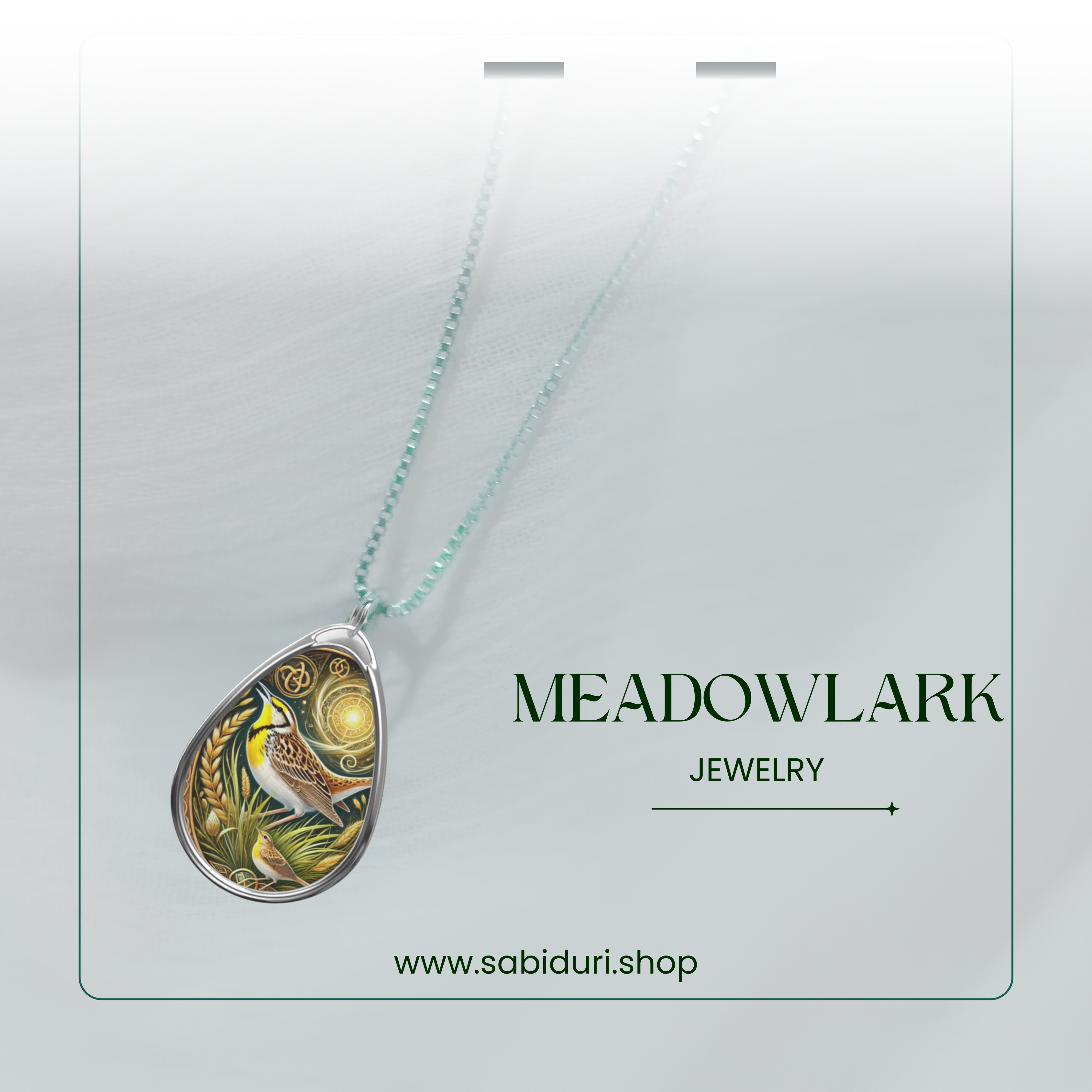 The meadowlark pendant necklace suspended against a soft, blurred white backdrop. The intricate bird design, surrounded by golden wheat and celestial patterns, stands out against the muted tones. The text "MEADOWLARK JEWELRY" and the website "www.sabiduri.shop" appear at the bottom.