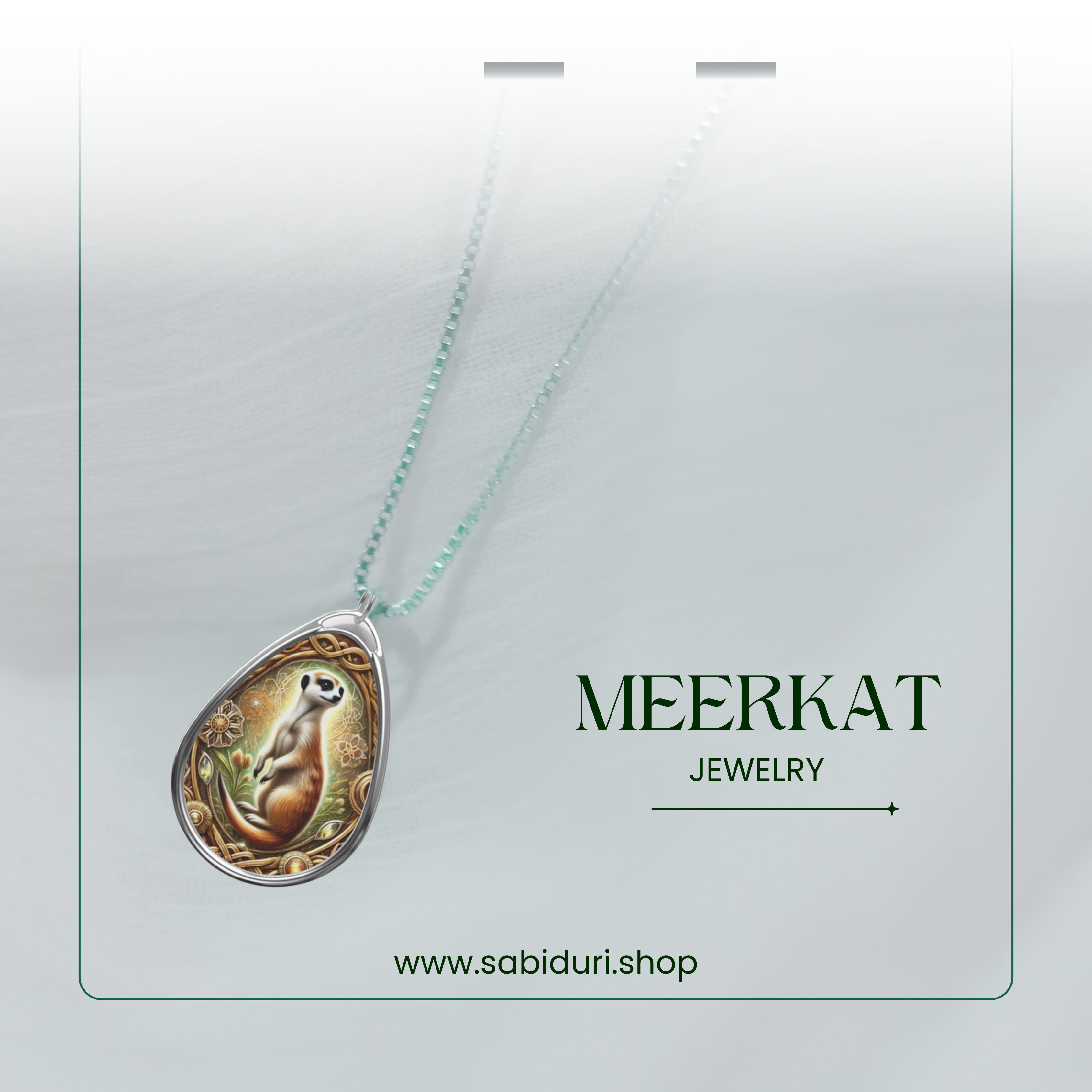 The meerkat necklace is suspended from a delicate silver chain against a soft, white background. The pendant’s intricate design, featuring a standing meerkat with golden floral patterns, is highlighted. The text "MEERKAT JEWELRY" and "www.sabiduri.shop" is present.