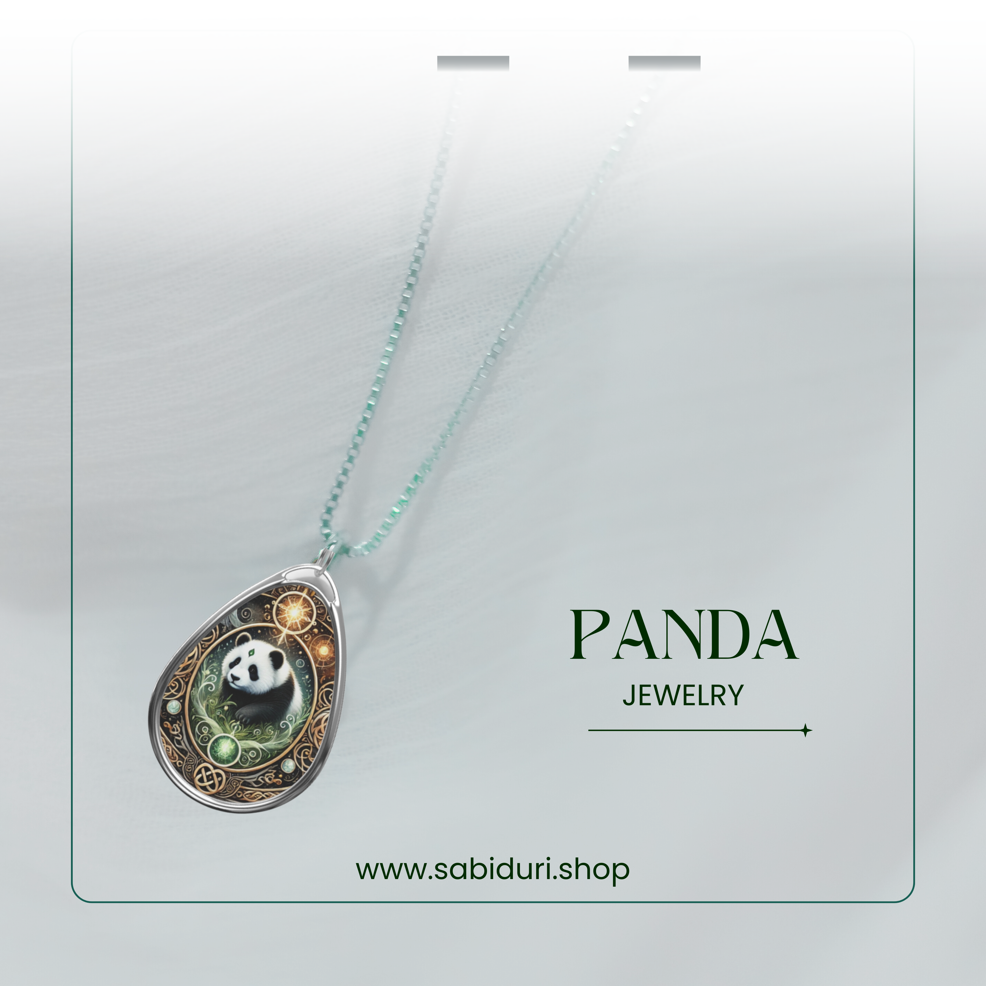 A teardrop-shaped pendant necklace featuring an intricately designed panda illustration, surrounded by golden celestial details and a green ornate frame. The necklace is displayed on a rich brown fabric with "PANDA NECKLACE" and "www.sabiduri.shop" in white text.