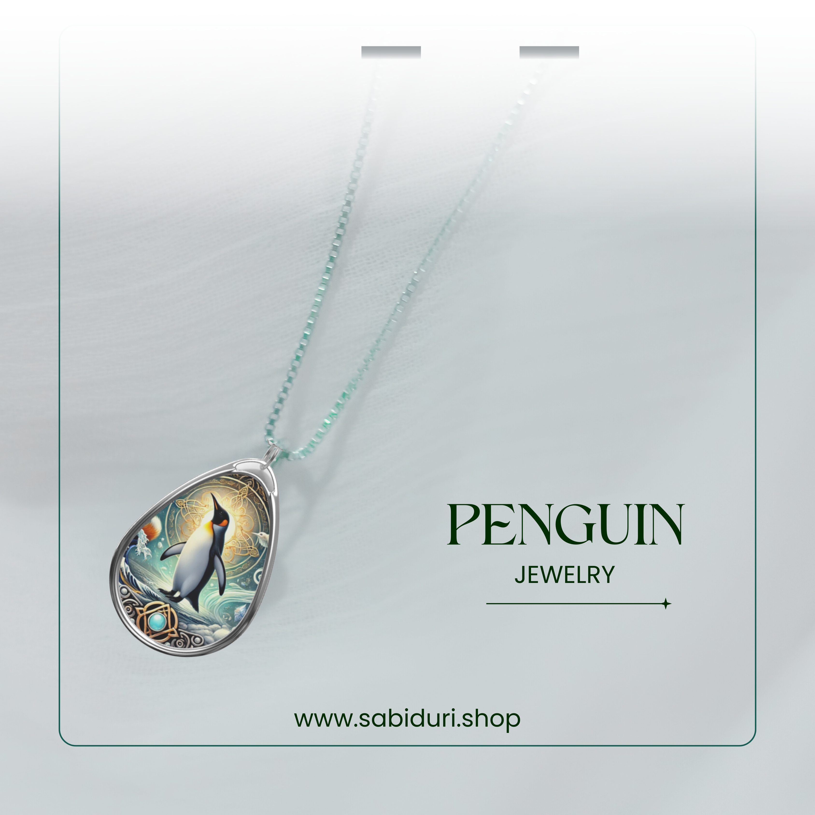 The penguin necklace is photographed against a soft, blurred white fabric background. The pendant glows with a radiant icy-blue and gold design, with the words "PENGUIN JEWELRY" and "www.sabiduri.shop" displayed.