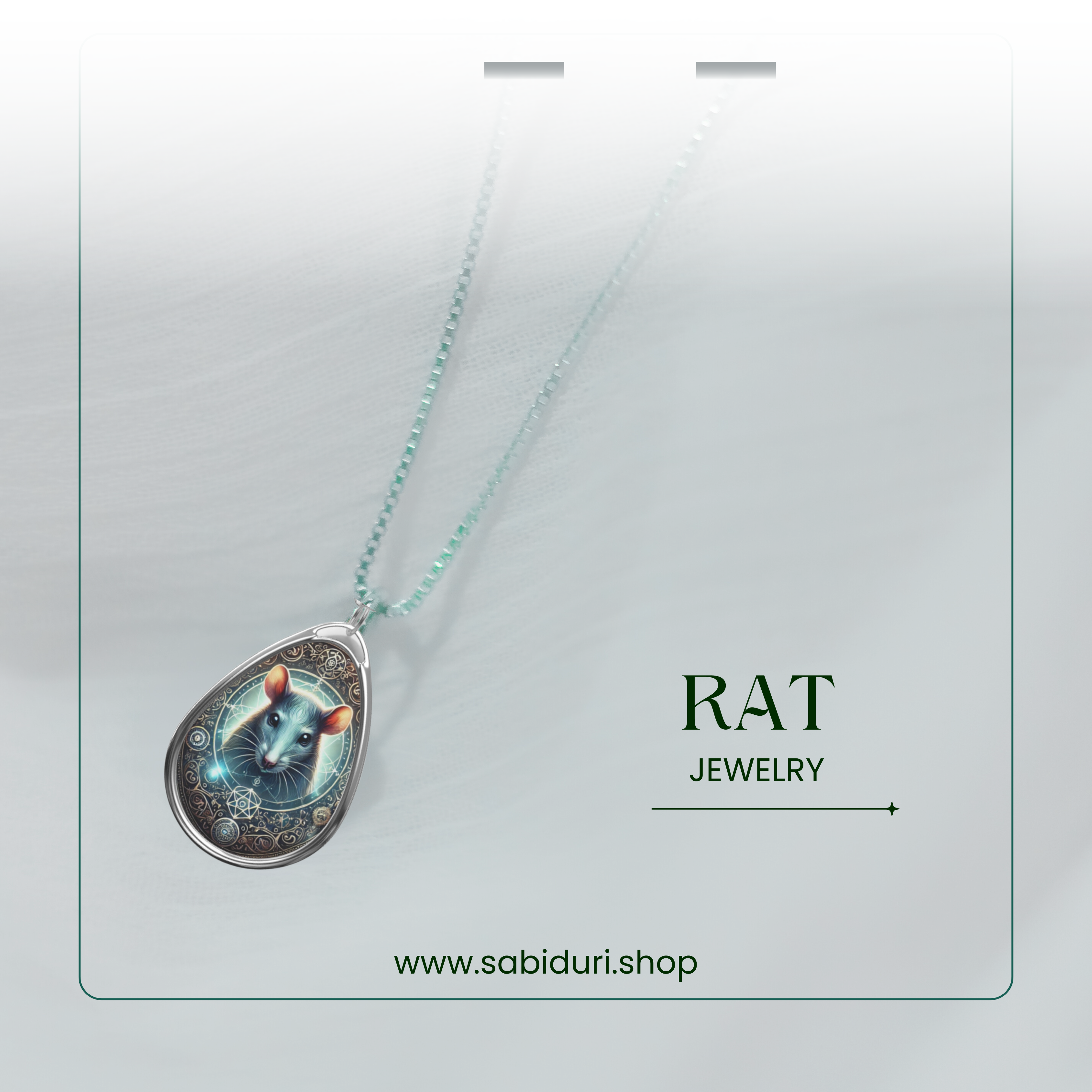 A delicate silver necklace with a teardrop pendant featuring a glowing rat illustration, adorned with celestial and geometric motifs. The necklace is displayed against a light, airy fabric background with "RAT JEWELRY" and "www.sabiduri.shop" written below.