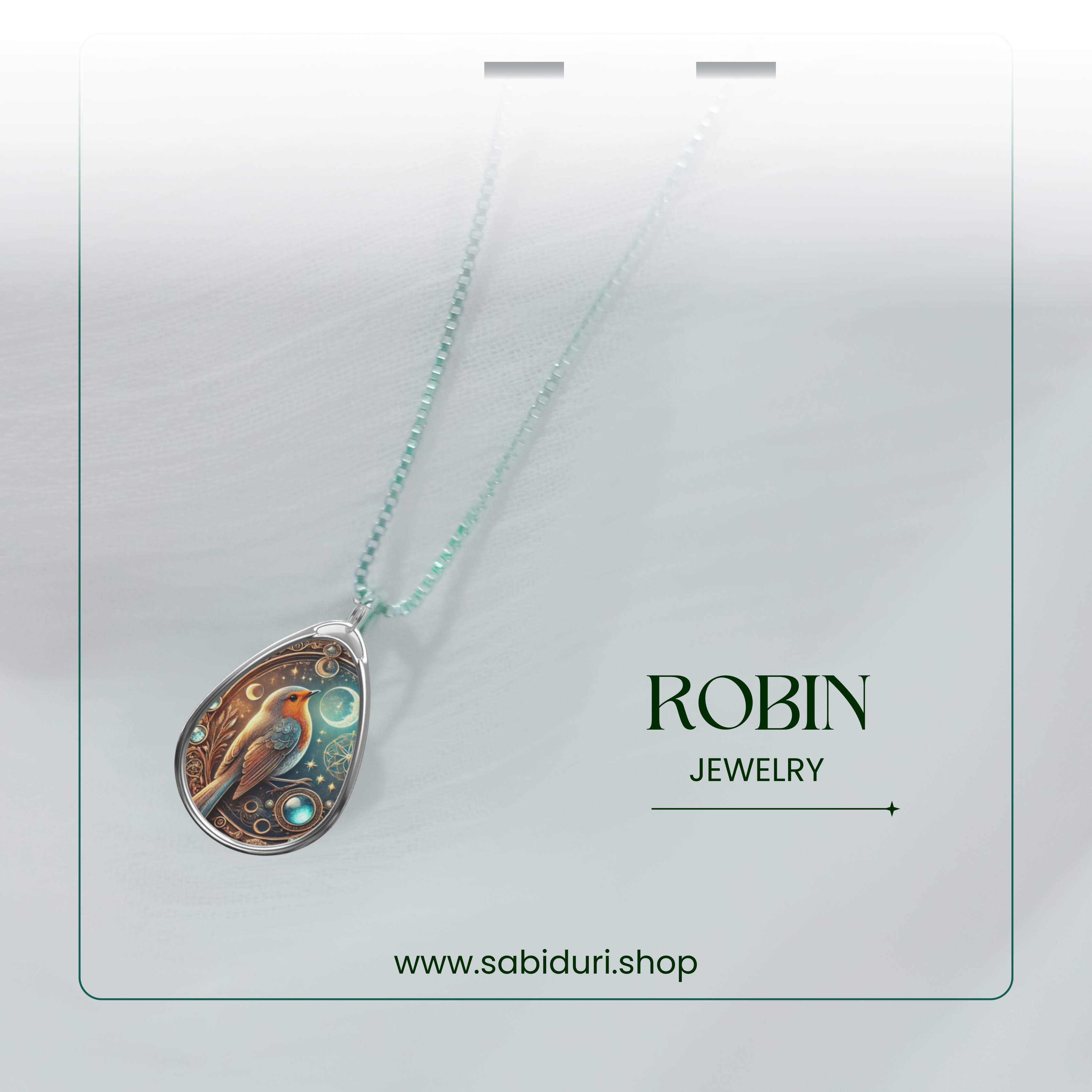 A close-up of the robin necklace pendant hanging from a delicate silver chain, set against a soft white fabric backdrop. The pendant design includes a robin, intricate celestial details, and a glowing gemstone. The text "ROBIN JEWELRY" and "www.sabiduri.shop" is placed nearby.