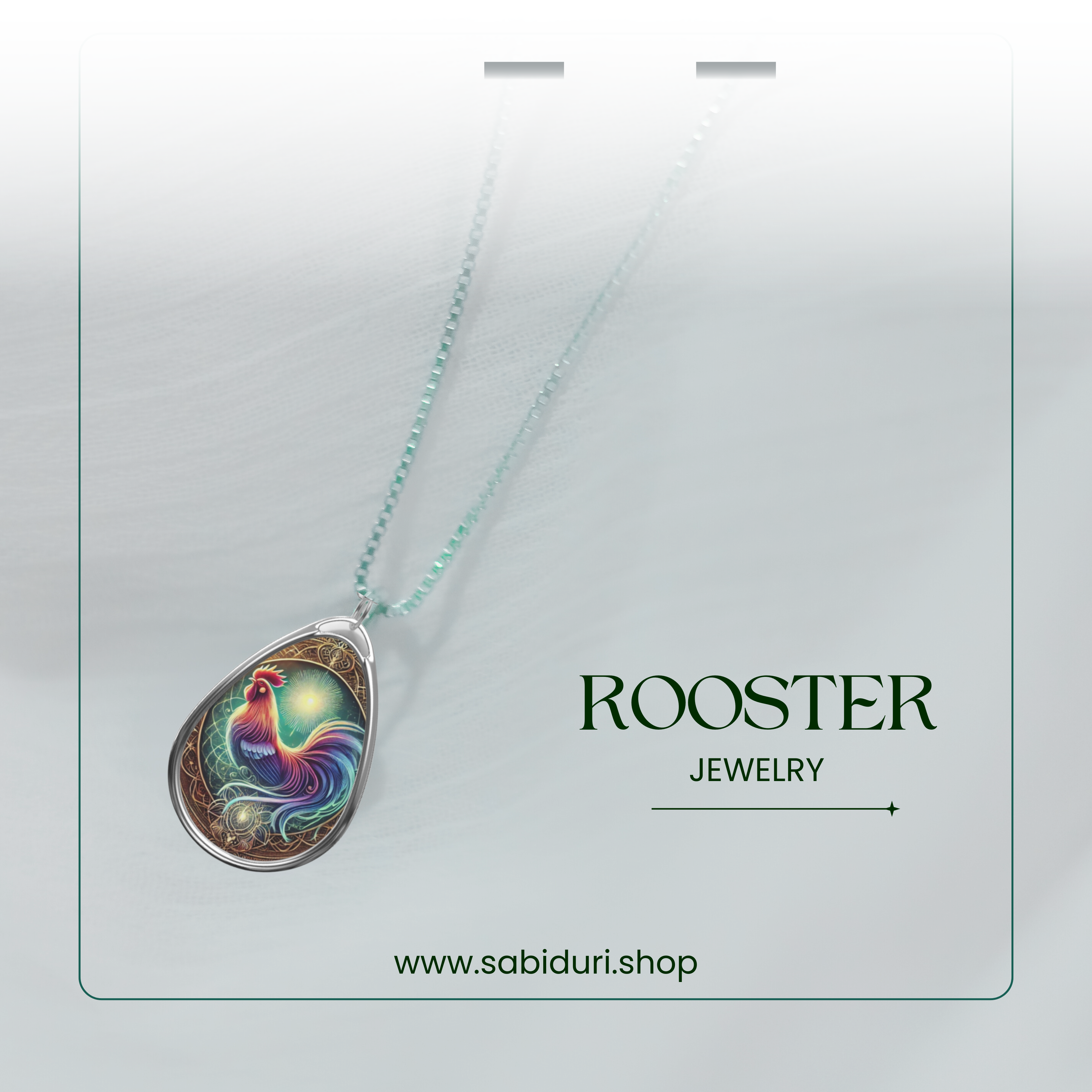 A close-up of the rooster pendant necklace, elegantly displayed on a light, airy background. The pendant’s intricate details include a multicolored rooster with a glowing aura, surrounded by ornamental patterns. The words "ROOSTER JEWELRY" and "www.sabiduri.shop" are placed beside it.