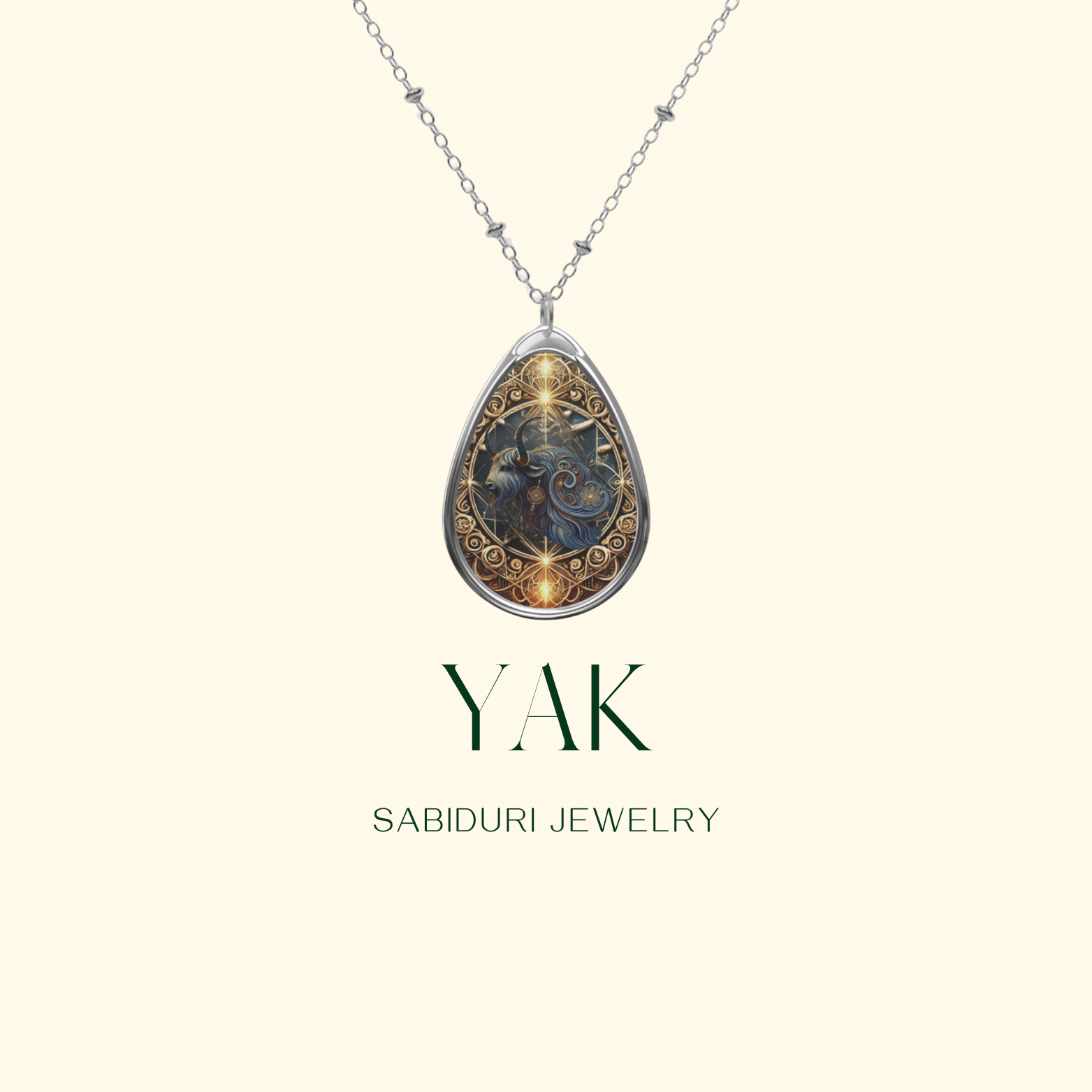 A silver necklace with a yak-themed pendant, adorned with golden filigree details, suspended against a clean, light-colored background. The text "YAK" and "SABIDURI JEWELRY" is displayed in a modern serif font.