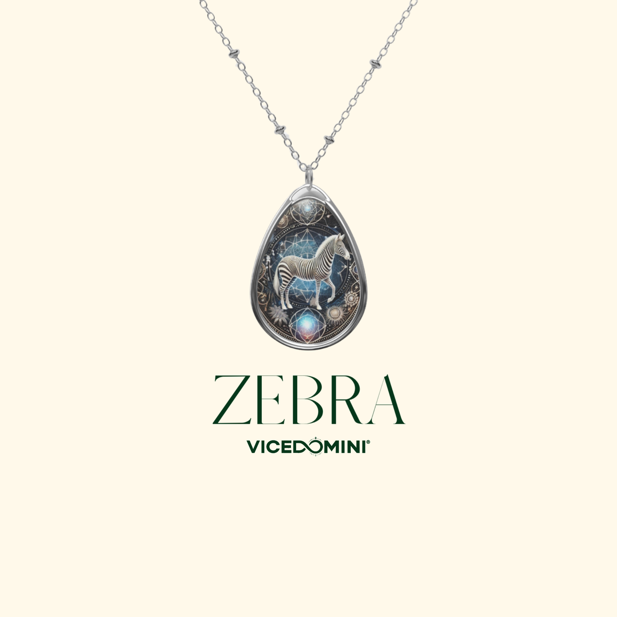 A teardrop-shaped silver pendant necklace featuring a zebra illustration over a blue and black celestial background, suspended from a silver chain on a light cream background. The brand name 'ZEBRA VICEDOMINI' is printed below the pendant.